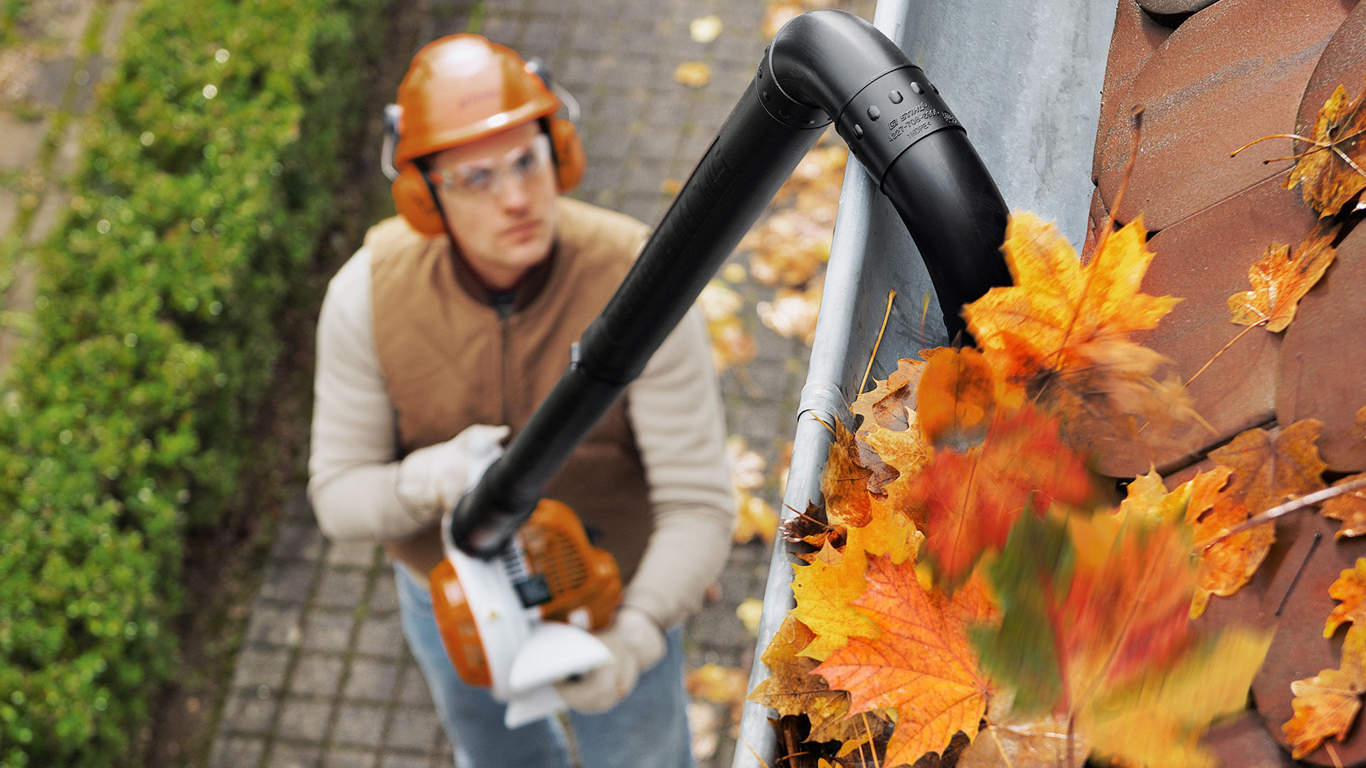 Mann mit STIHL Benzin-Laubbläser BG 56 reinigt Regenrinne