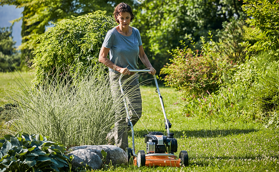 Donna che tosa il prato del suo giardino in estate utilizzando il tosaerba con funzione mulching STIHL RM 2 R