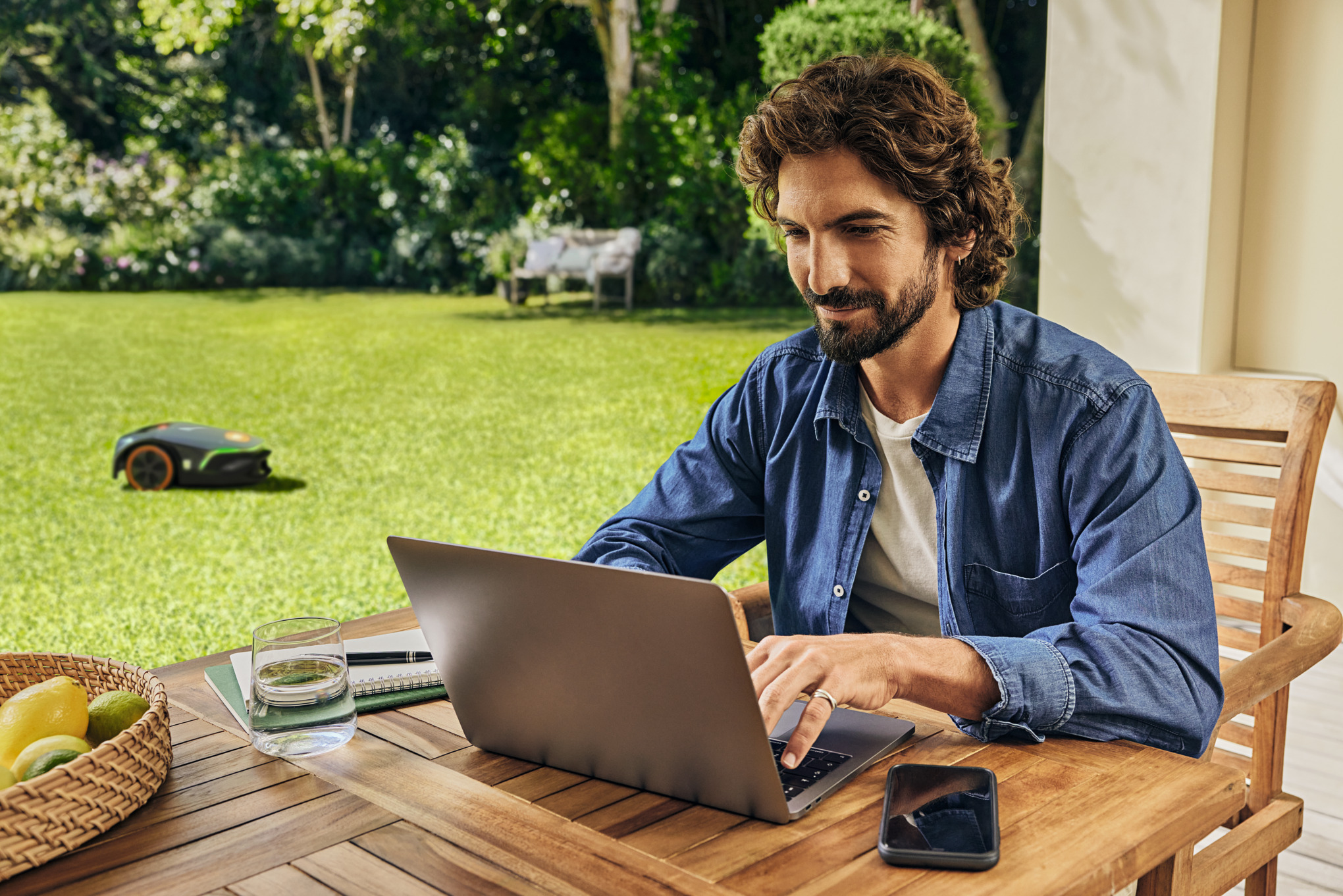 Ein Mann arbeitet an seinem Laptop im Garten.