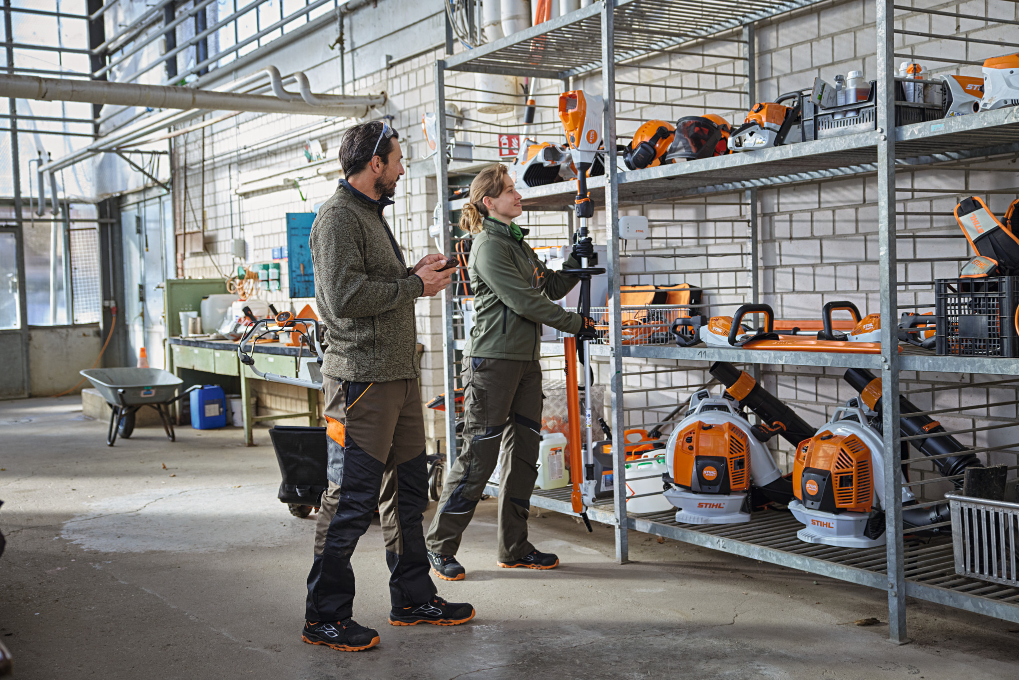  Professionisti del GaLaBau in un magazzino controllano lo stato dei prodotti utilizzando l'app STIHL connected.