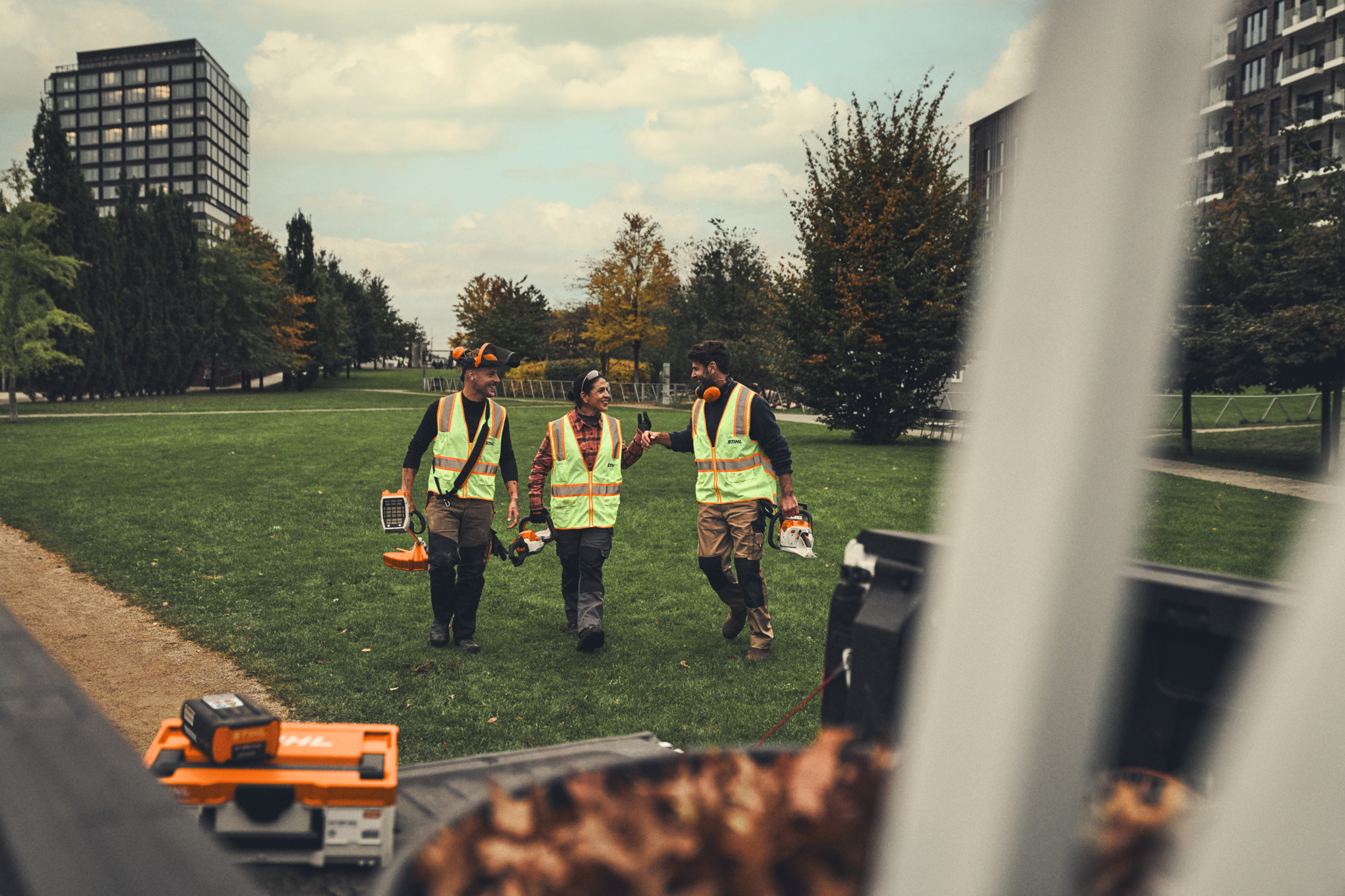 Cinque professionisti STIHL muniti di attrezzi a batteria che percorrono una strada