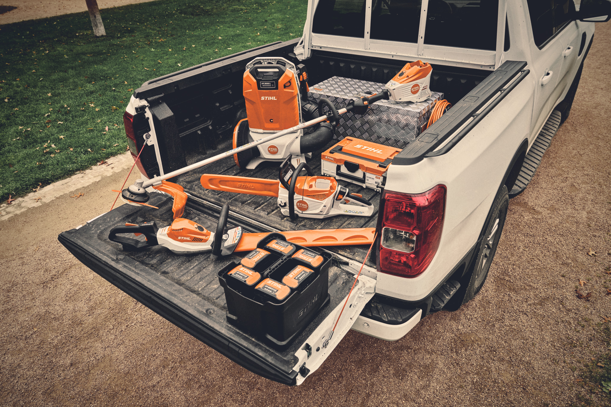Diversi apparecchi a batteria del sistema STIHL AP e le relative batterie sulla superficie di carico di un veicolo