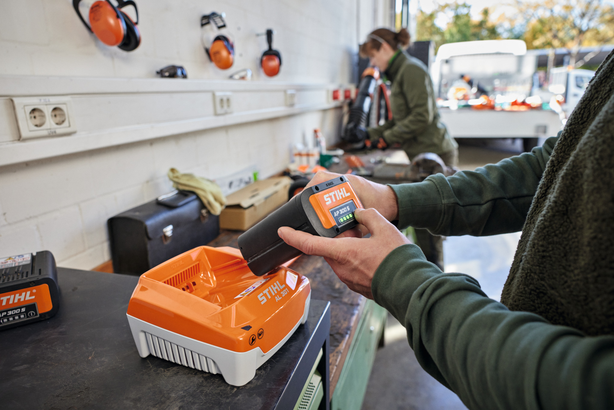 Una persona inserisce una batteria STIHL AP 300 S in un caricabatterie rapido STIHL AL 301