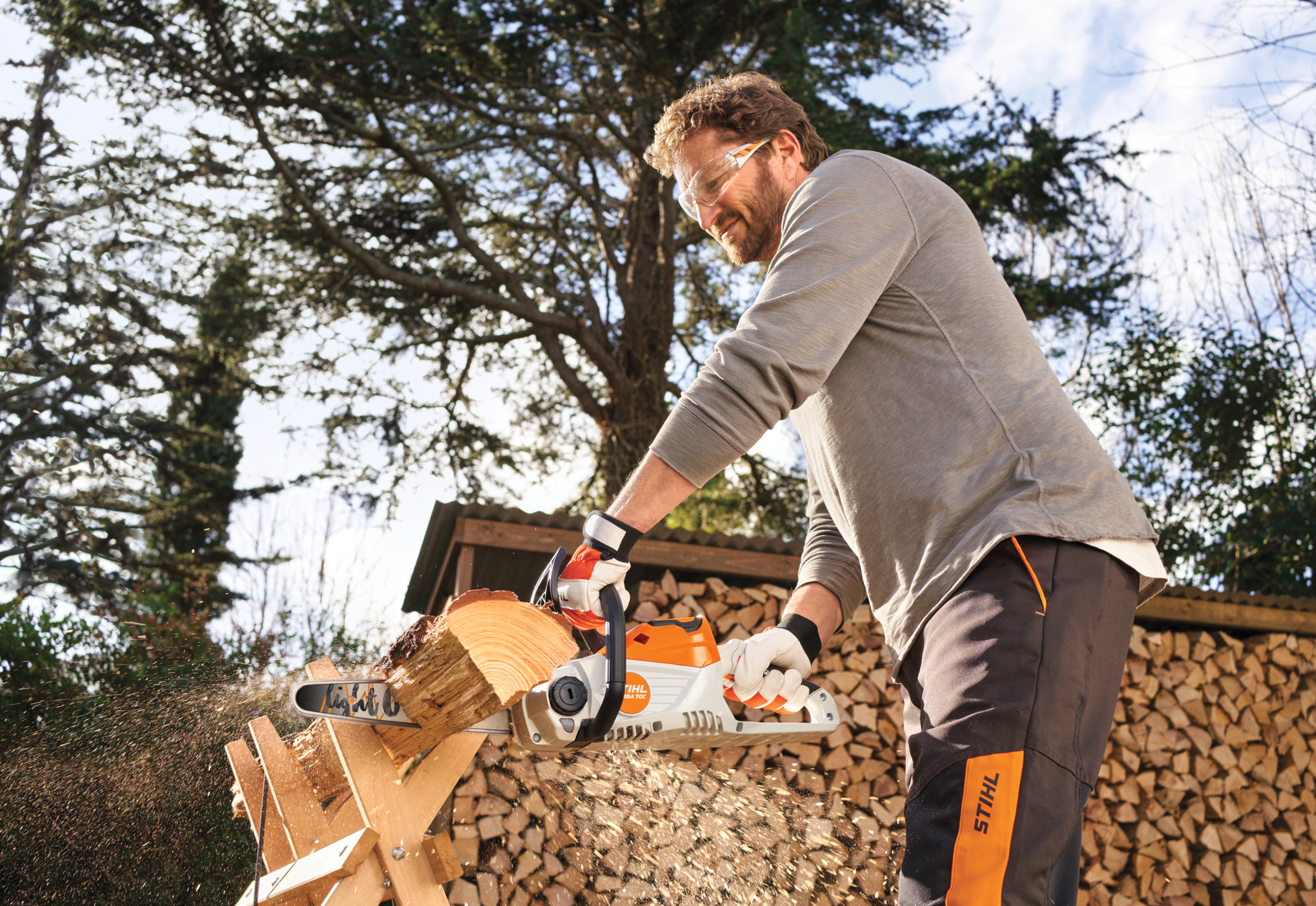 Uomo che sega legno su un cavalletto con una motosega STIHL