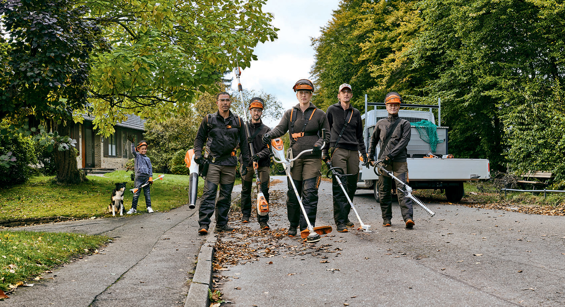 Un team di giardinieri e paesaggisti con apparecchi a batteria STIHL percorre una strada