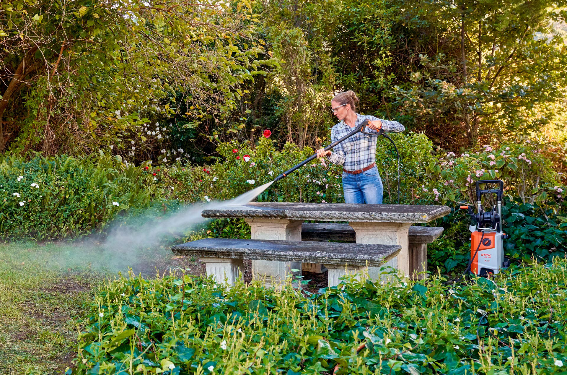 Donna che pulisce l'esterno dei suoi mobili da giardino con un'idropulitrice STIHL