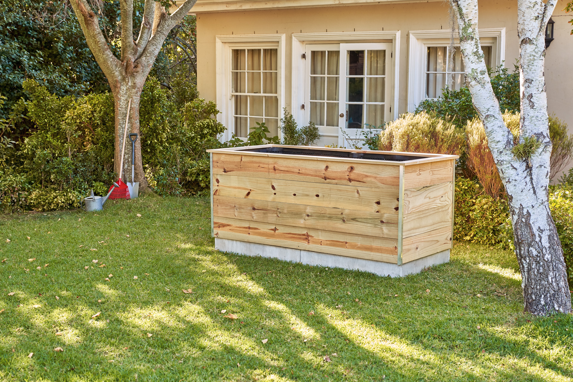 Aiuola rialzata in legno fai da te nel giardino di fronte a una casa