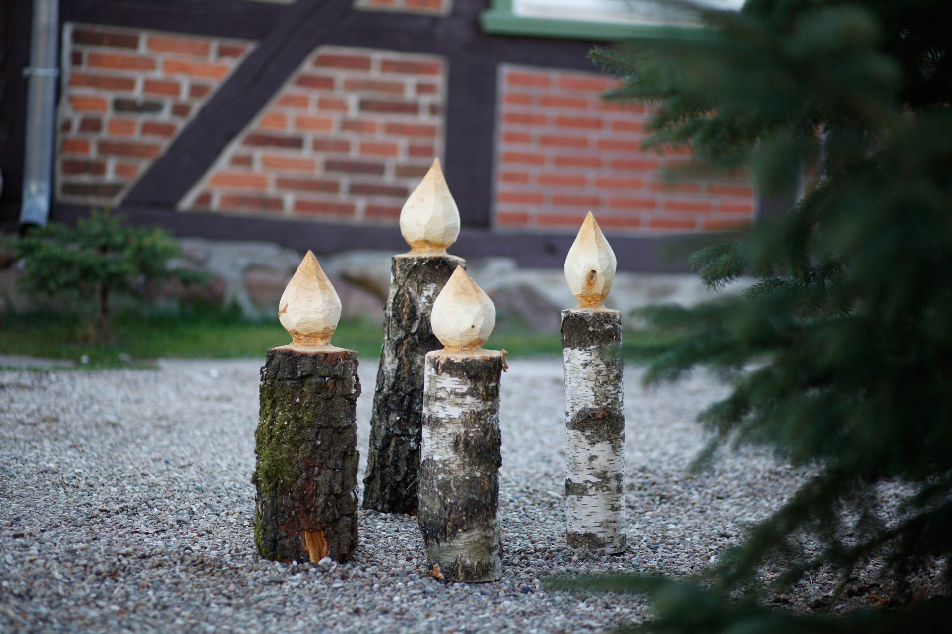 Quattro candele di legno fai da te accanto a un abete