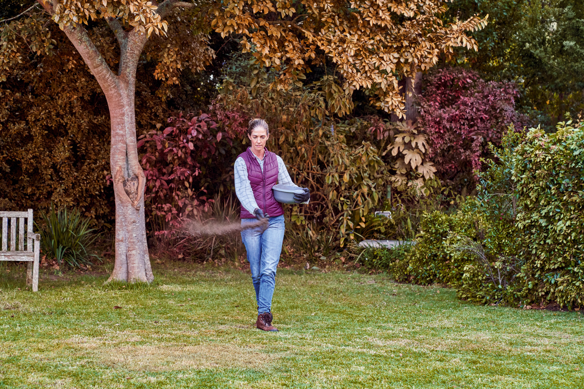 Donna che sparge il fertilizzante nel suo giardino