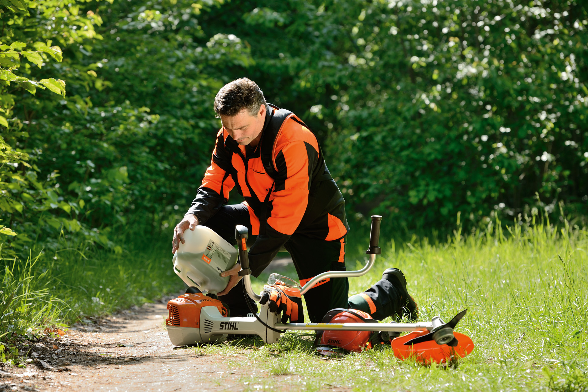 Uomo che rifornisce il decespugliatore STIHL con una miscela di benzina e olio