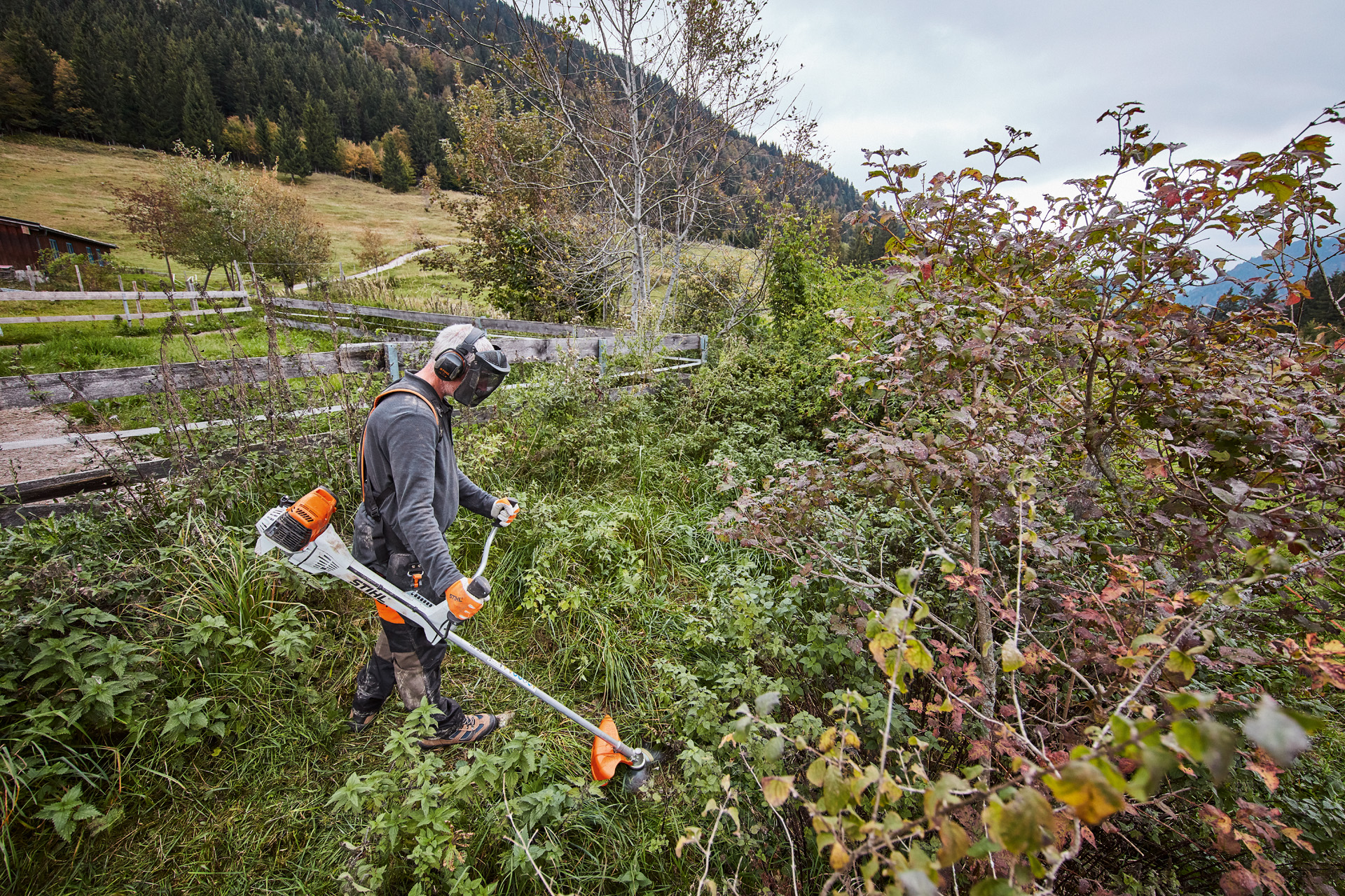 Uomo con dispositivi di protezione individuale che falcia sterpaglia fitta con un tagliabordi a benzina STIHL FS 311