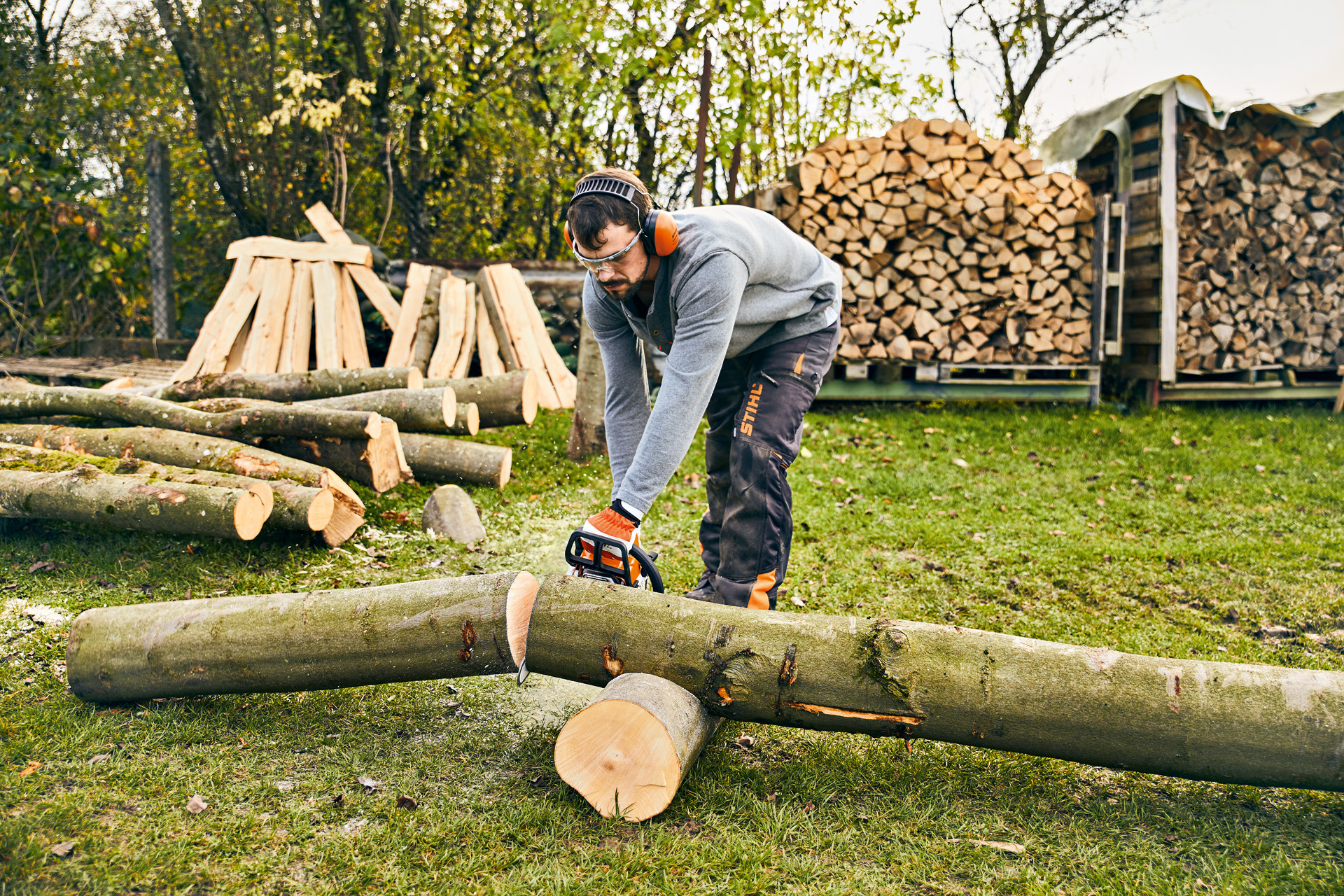 Uomo con DPI taglia un tronco di legno con una motosega a benzina STIHL MS 180