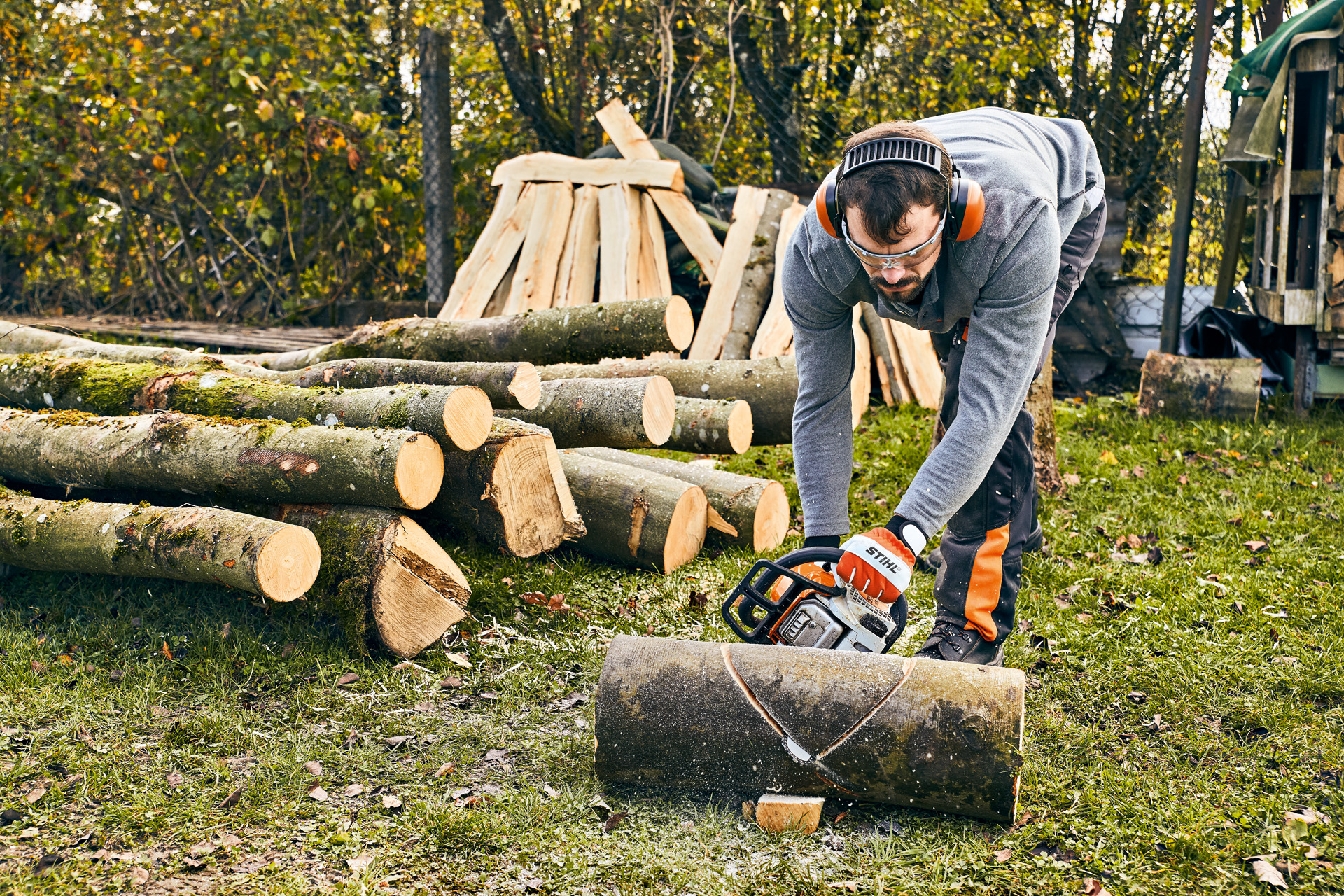 Uomo taglia un tronco con la motosega STIHL