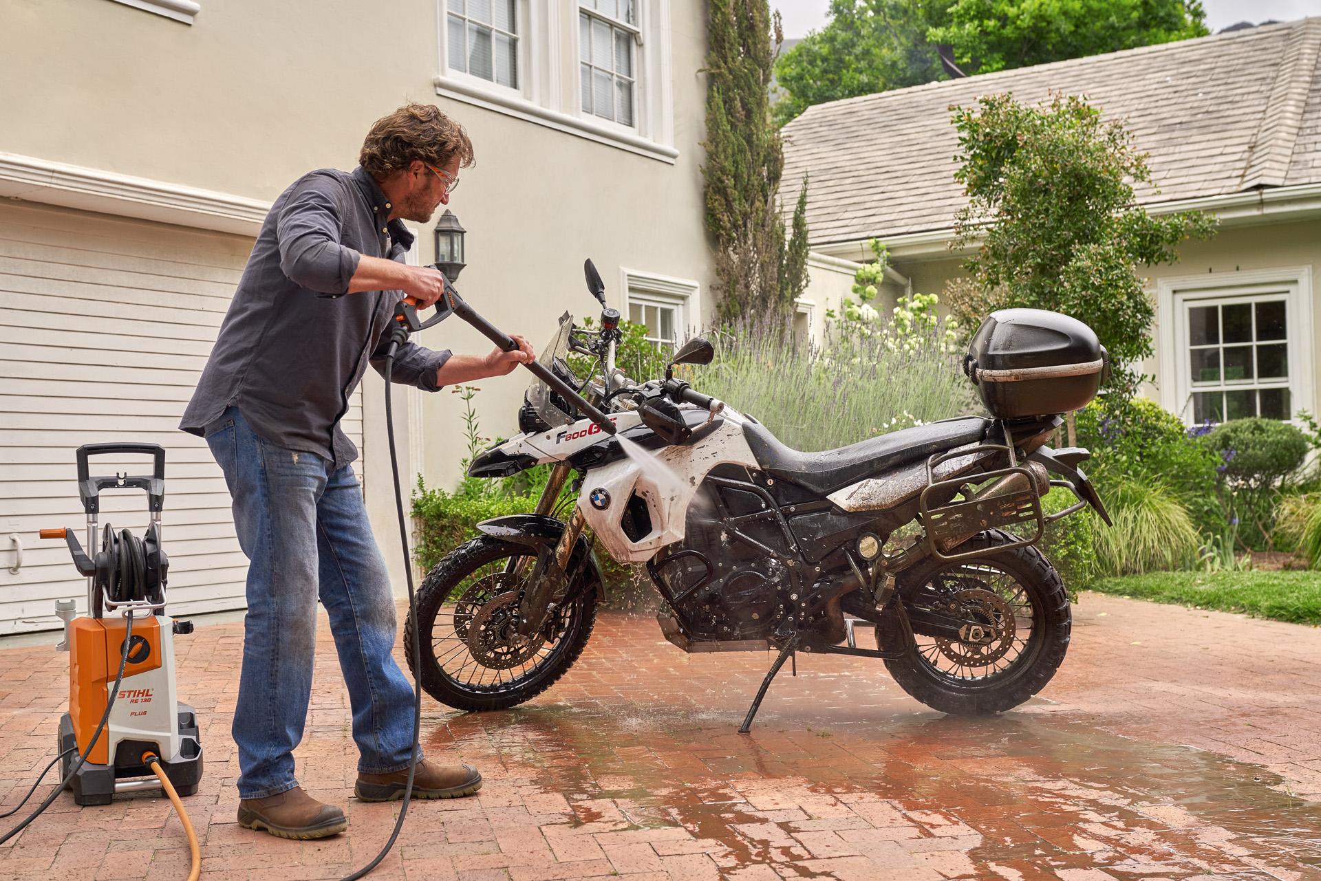 Uomo davanti a una casa che lava la moto con un'idropulitrice STIHL RE 130 plus
