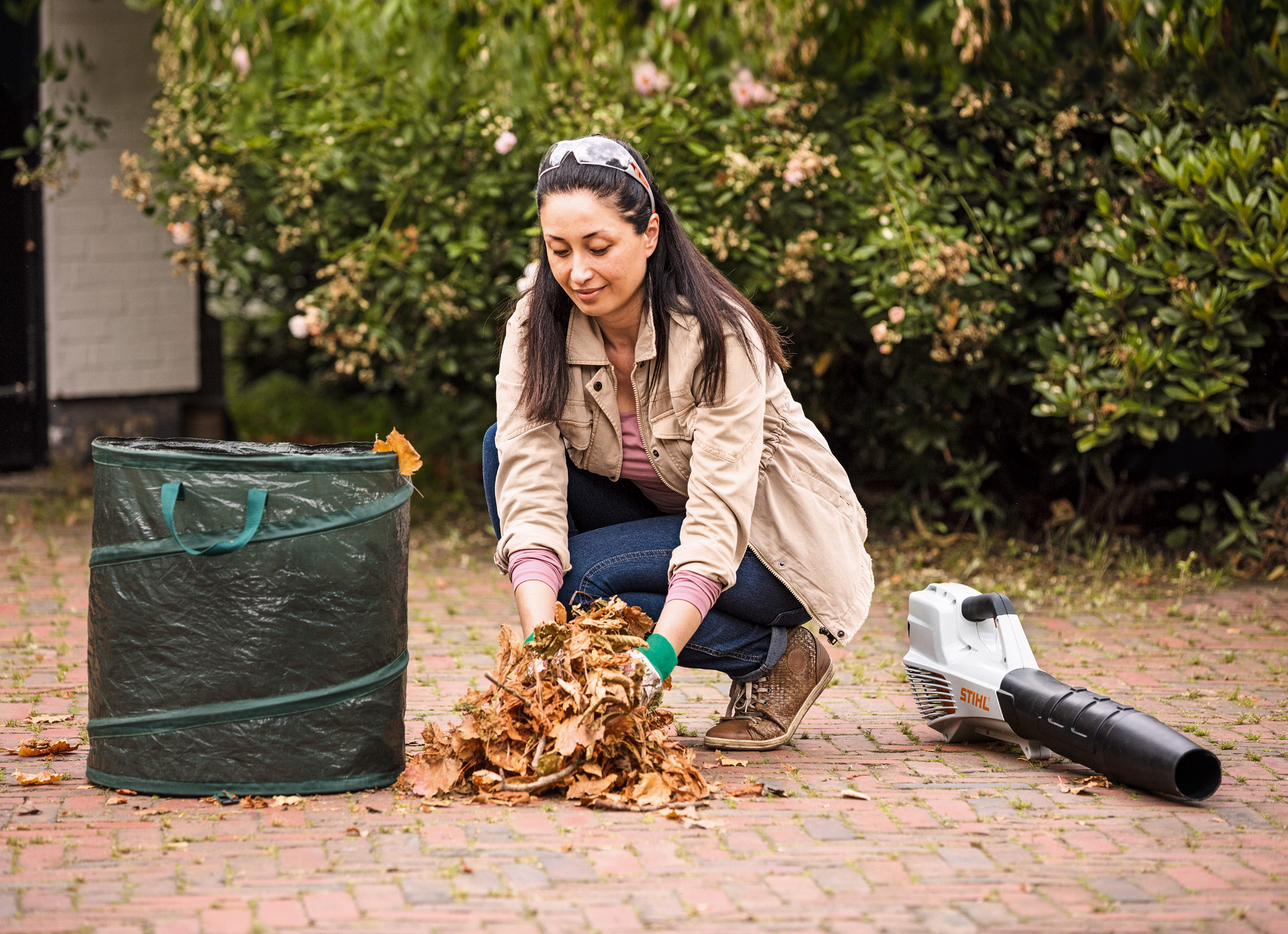  Donna che si occupa dello smaltimento delle foglie con l'ausilio di un sacco e del soffiatore STIHL BGA 56