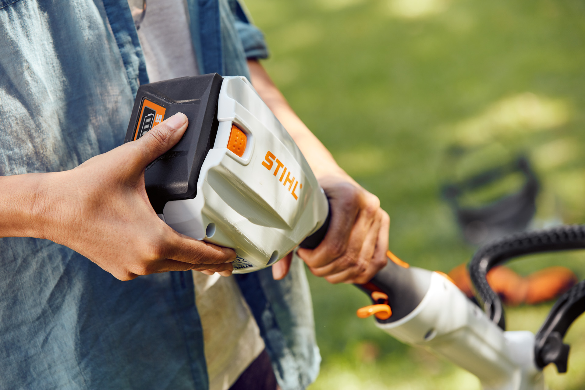 Persona che sorregge il decespugliatore senza fili STIHL FSA 56 e sfiora la batteria con la mano