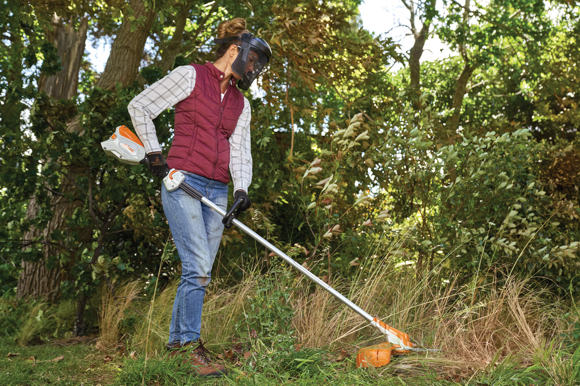 Donna che falcia un prato incolto con un decespugliatore STIHL