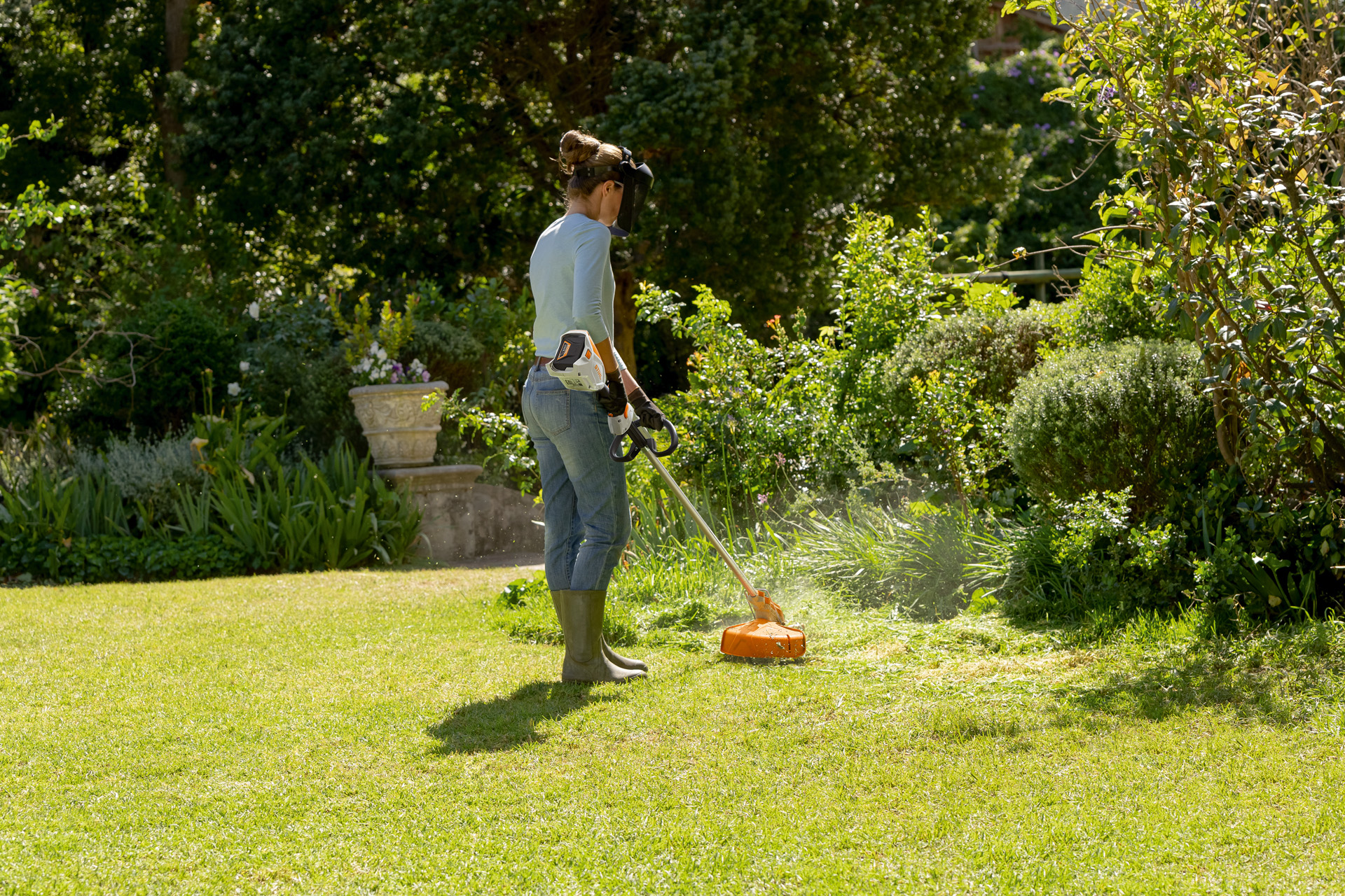 Donna che falcia il prato con un decespugliatore a batteria STIHL FSA 60 R