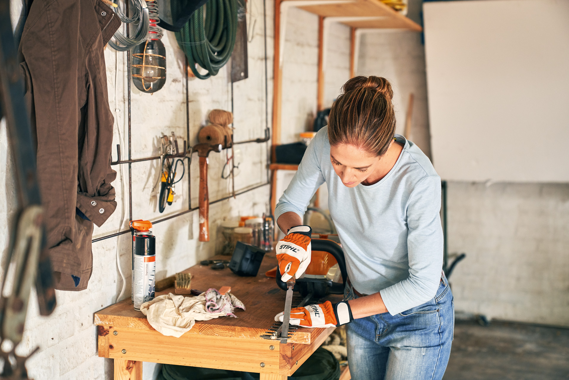 Donna che affila la lama di un tagliasiepi senza fili STIHL HSA 56 su un banco da lavoro