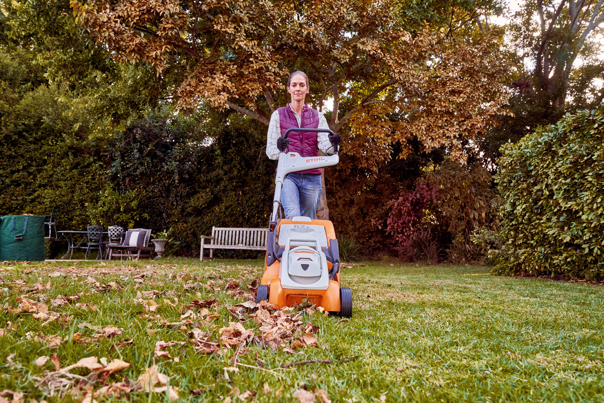 Donna che utilizza il tosaerba a batteria STIHL RMA 339 C in un giardino per la cura del prato in autunno