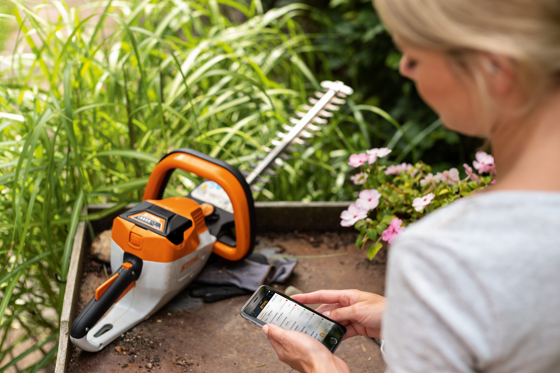 Una donna che registra il tosasiepi STIHL con l'app STIHL sullo smartphone