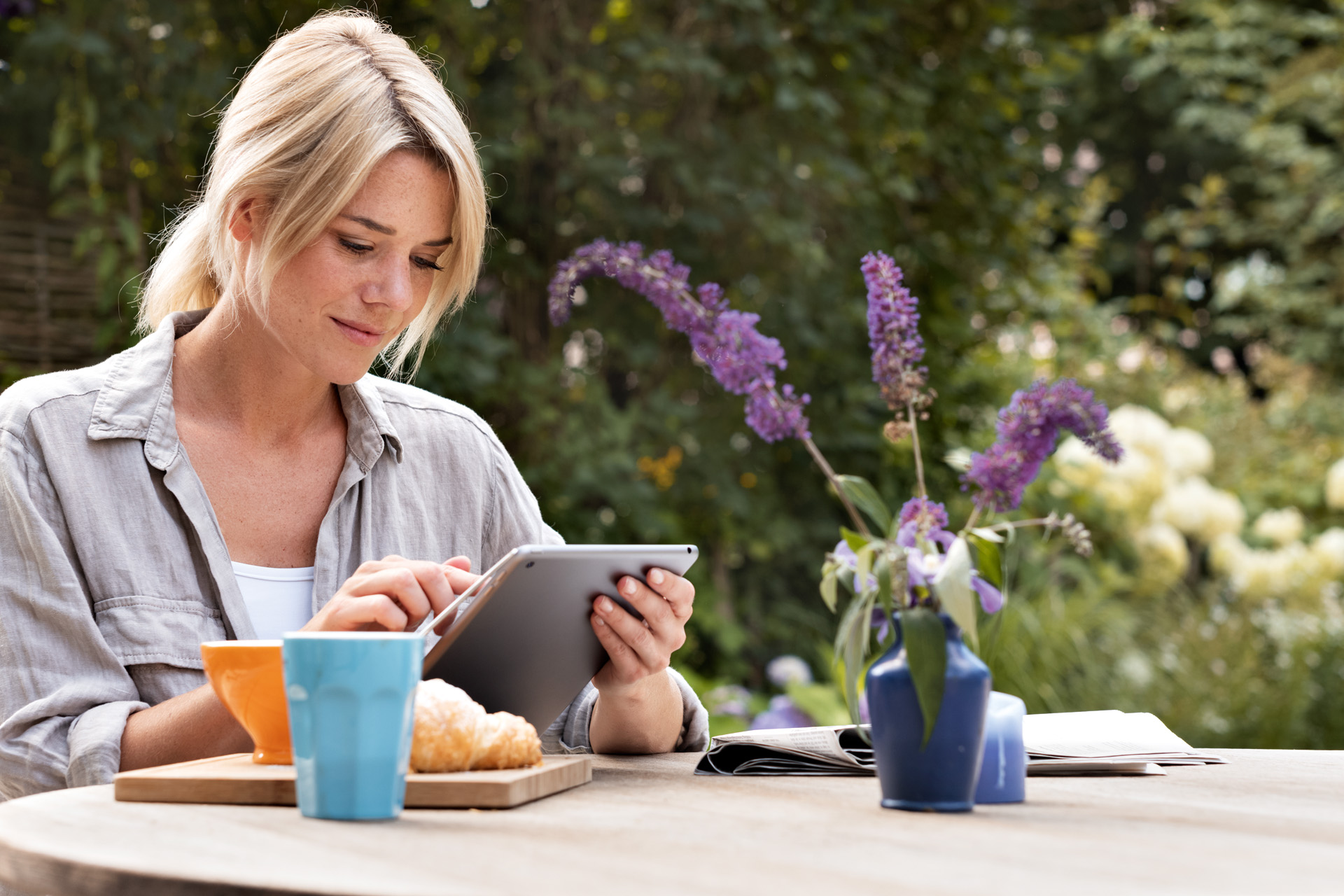 Donna che usa un tablet a colazione in giardino