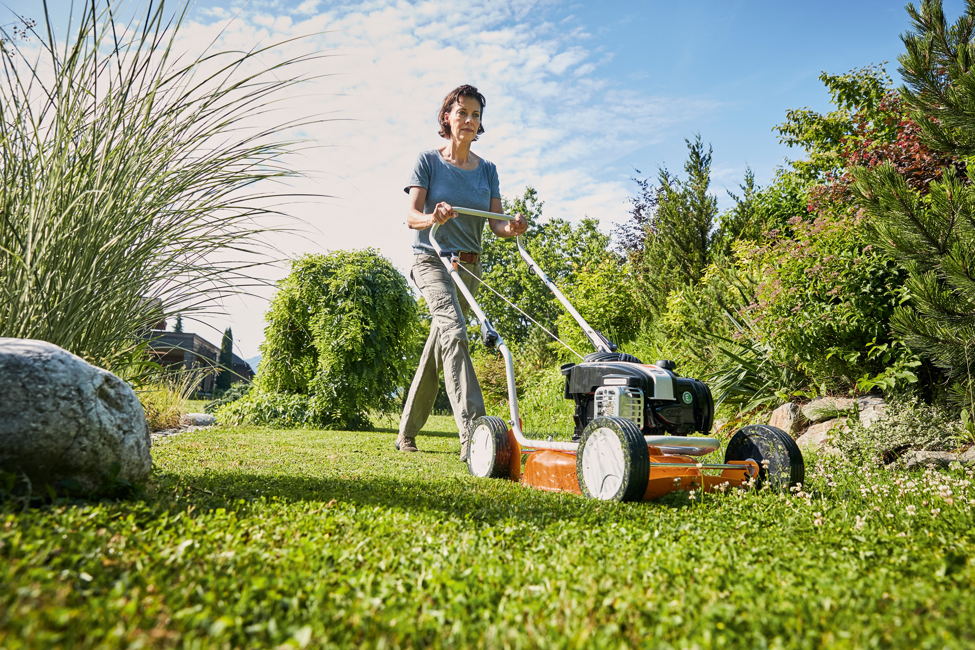 Donna che effettua il mulching con un tosaerba a benzina con funzione mulching STIHL RM 2 R su un terreno verde