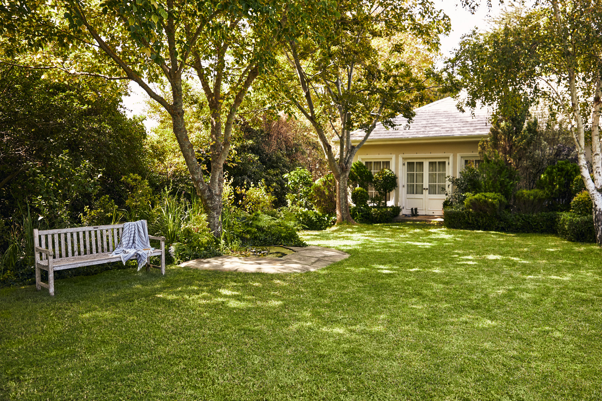 Casetta con giardino, in primo piano una panca da giardino su prato verde