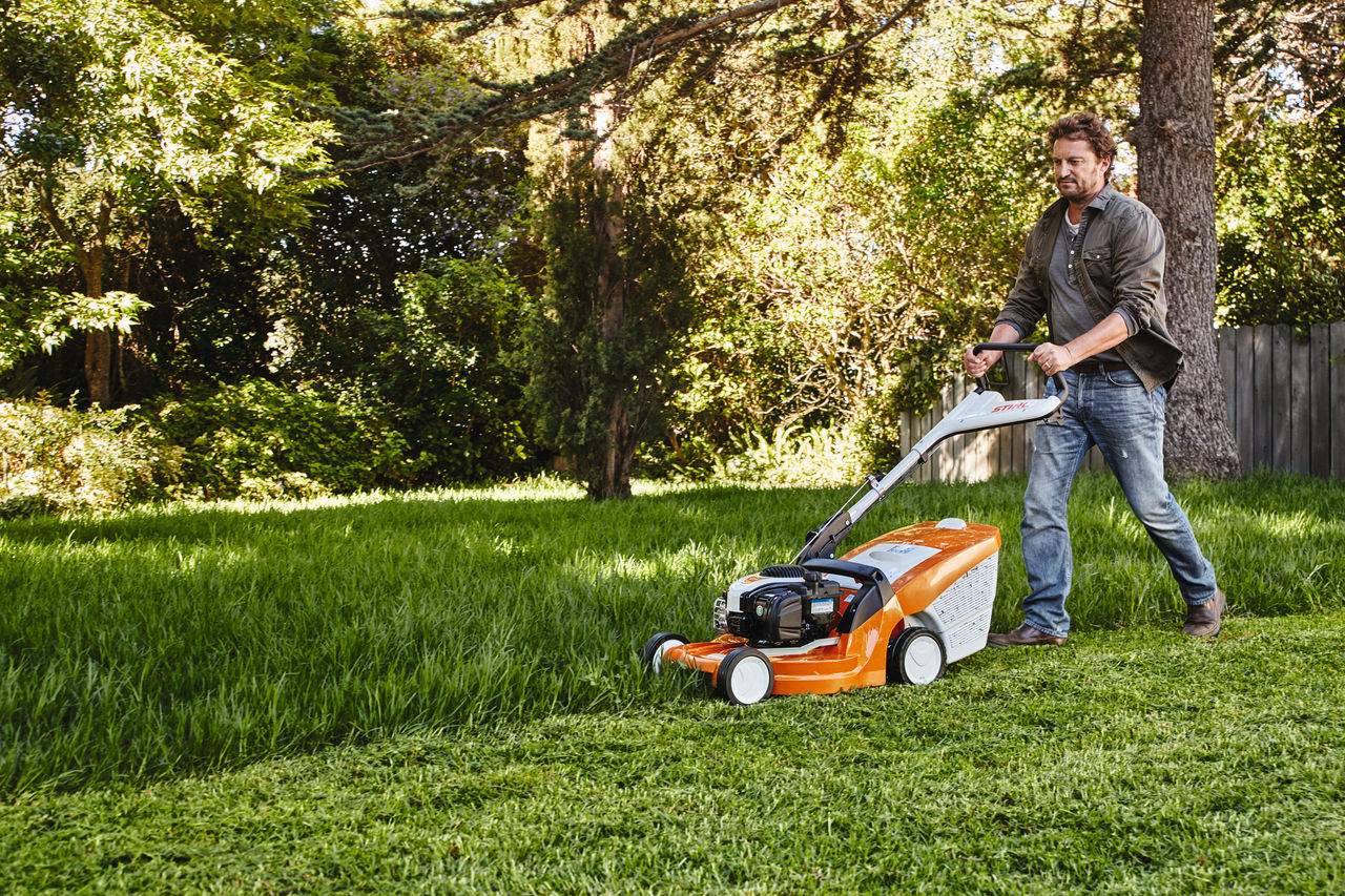 Un uomo taglia il prato in giardino con un tosaerba STIHL 