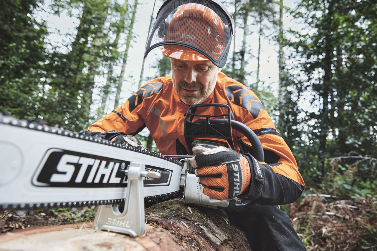 Un uomo con equipaggiamento di protezione lavora con una motosega STIHL in un bosco