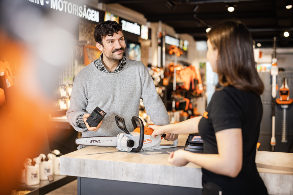 Il rivenditore mostra al cliente la motosega a batteria