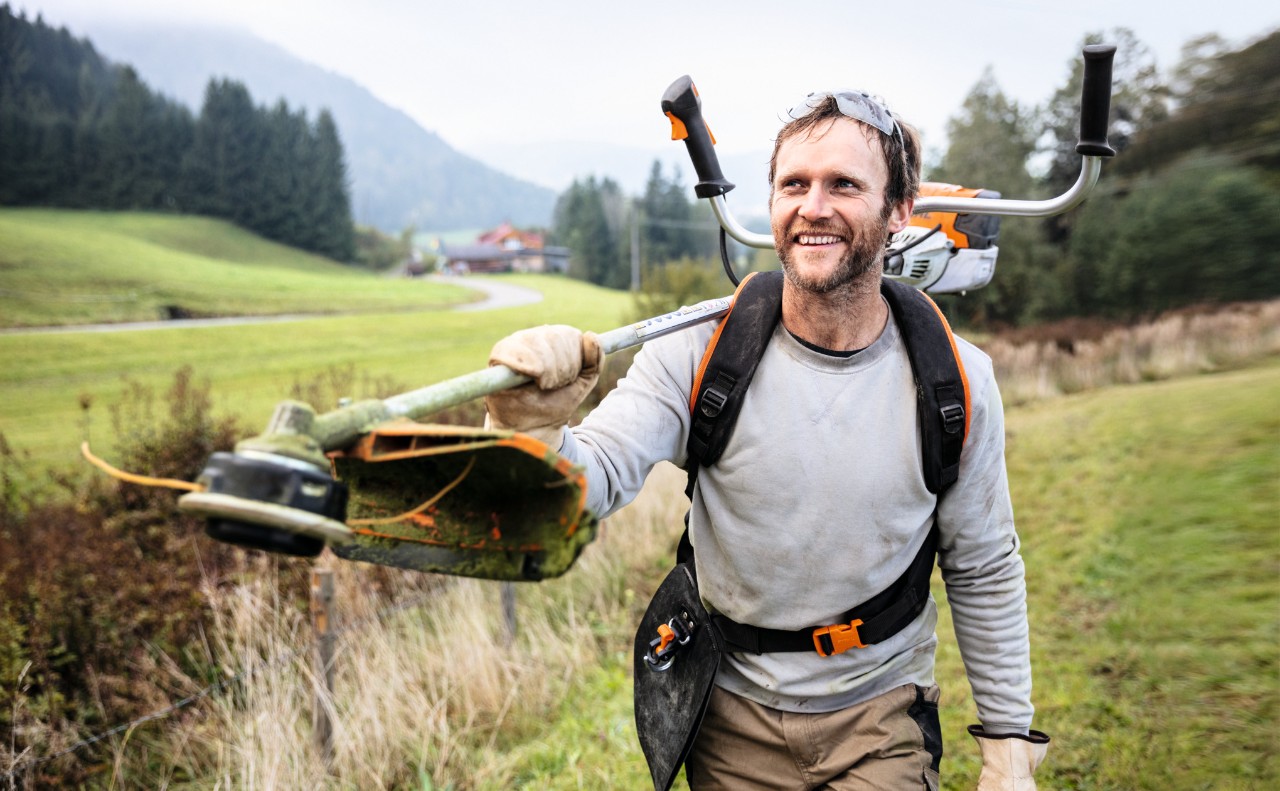 Uomo che cammina su un campo sorridendo con il decespugliatore STIHL FS 91