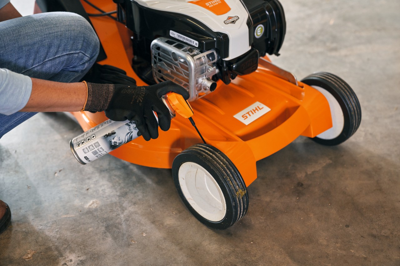 Donna che ripone il suo tosaerba a benzina STIHL RM 448 TC in un garage