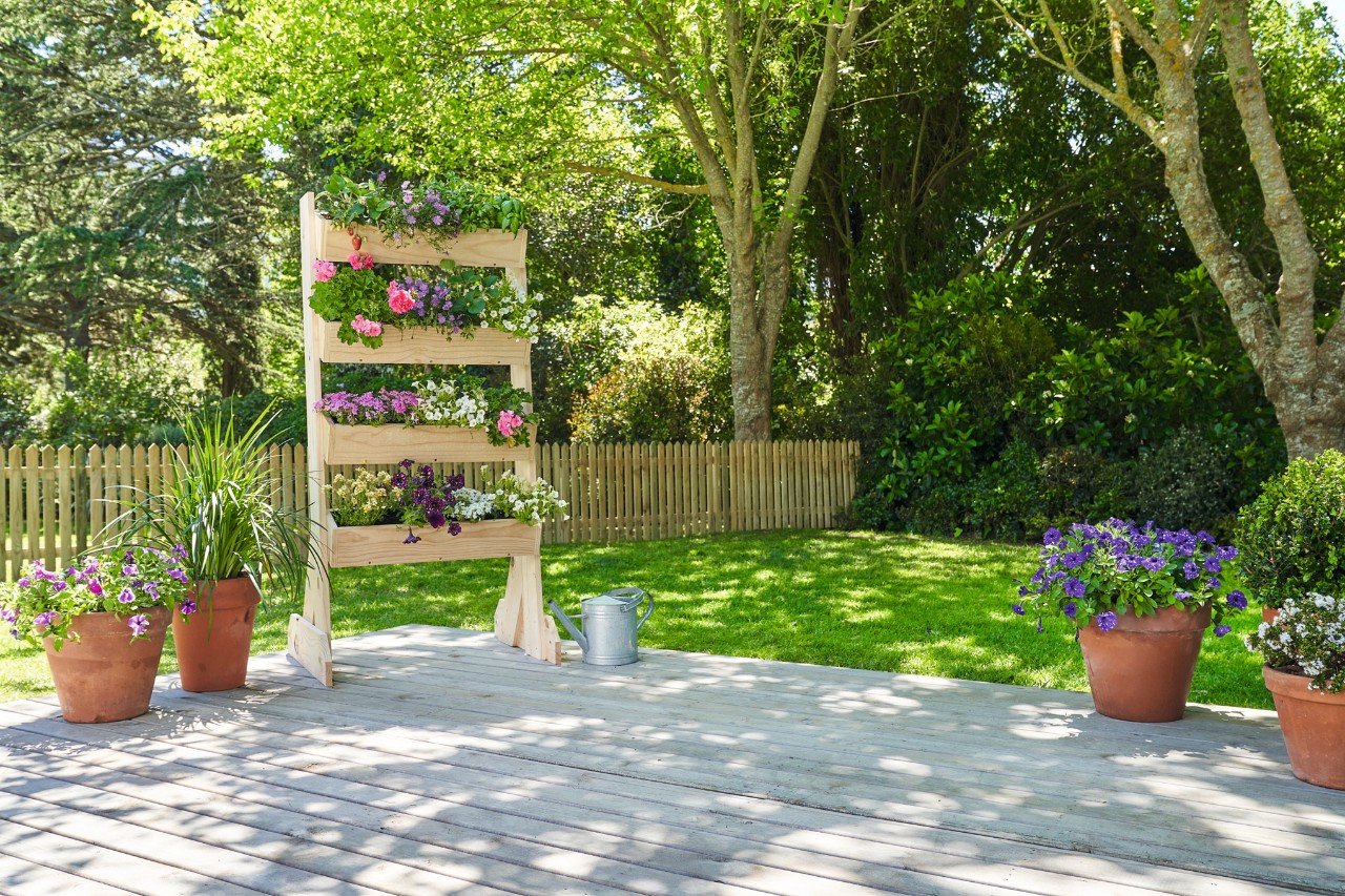 Scaffale per piante fai da te su una terrazza in legno in un giardino verde