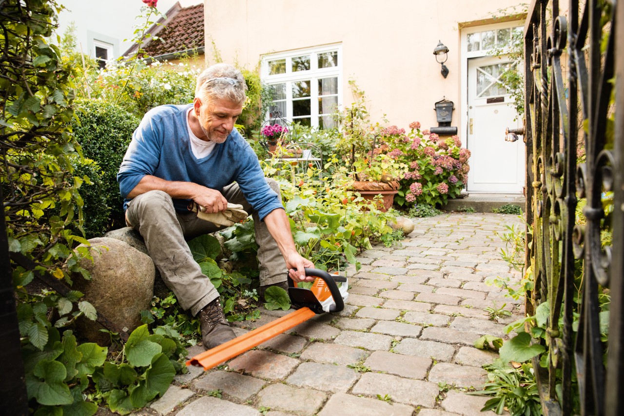 Uomo con tagliasiepi elettrico STIHL HSA 45 della linea AI davanti a una casa