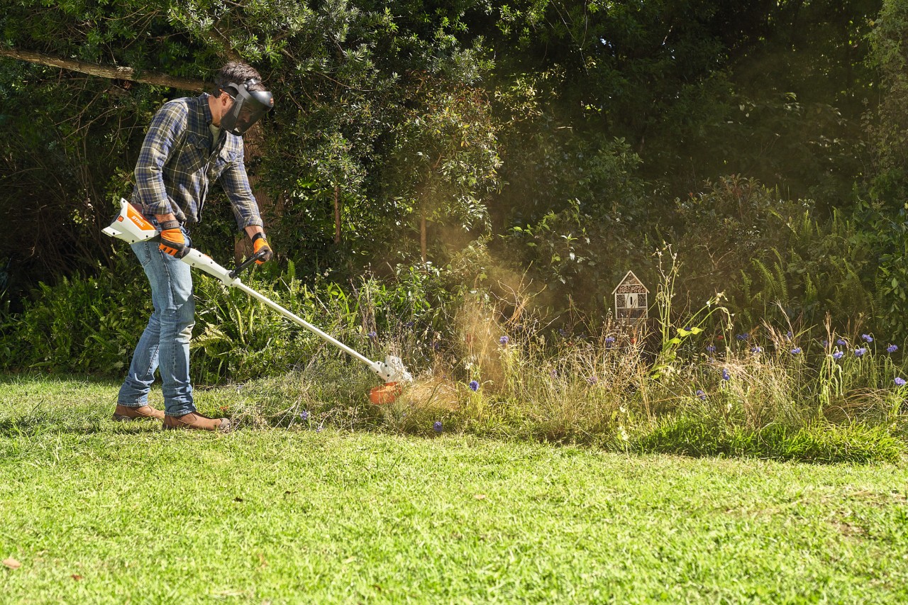 Uomo che falcia un prato di fiori selvatici con STIHL FSA 57
