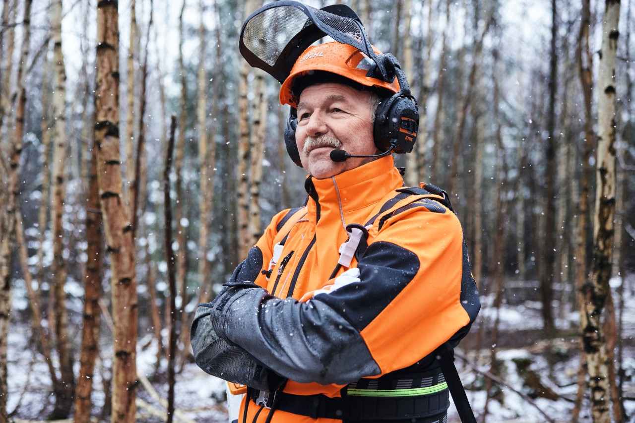 Il responsabile della silvicoltura Martin Nolte in piedi nel bosco in abbigliamento STIHL con le braccia conserte