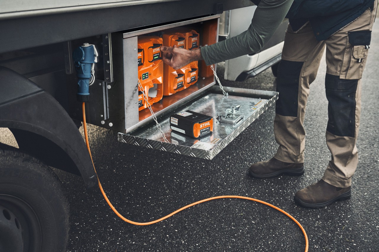Un uomo estrae una batteria STIHL AP 500 carica dal box di ricarica 